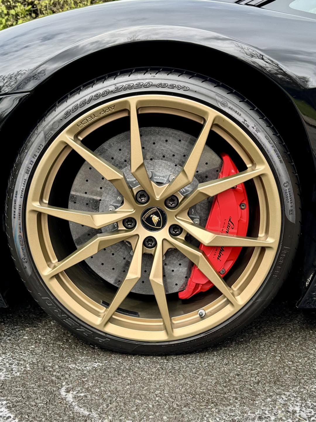 Close-up of a Lamborghini Aventador bronze wheel and red carbon ceramic brake caliper