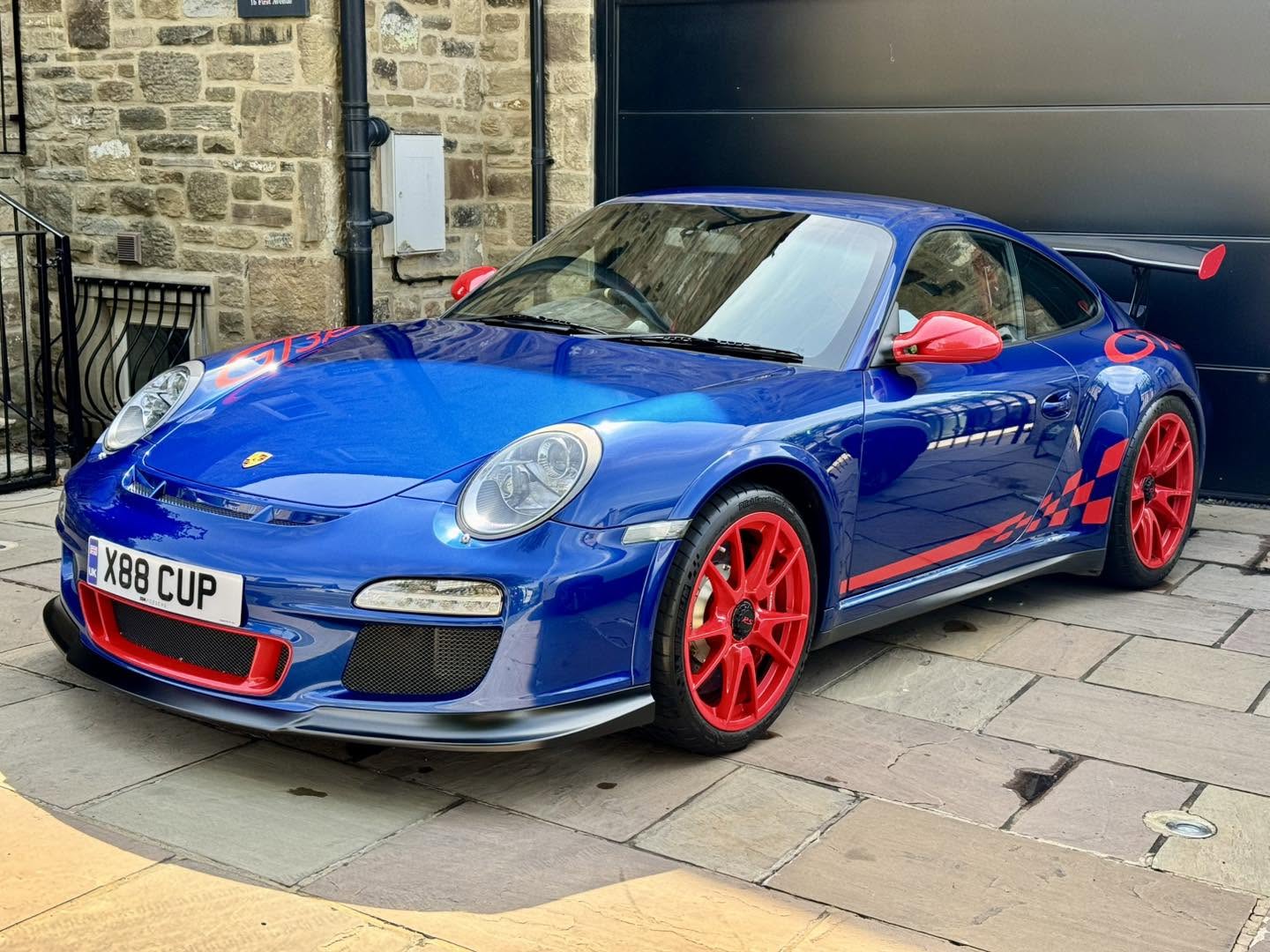 Blue Porsche 911 GT3 RS with red wheels after paint correction